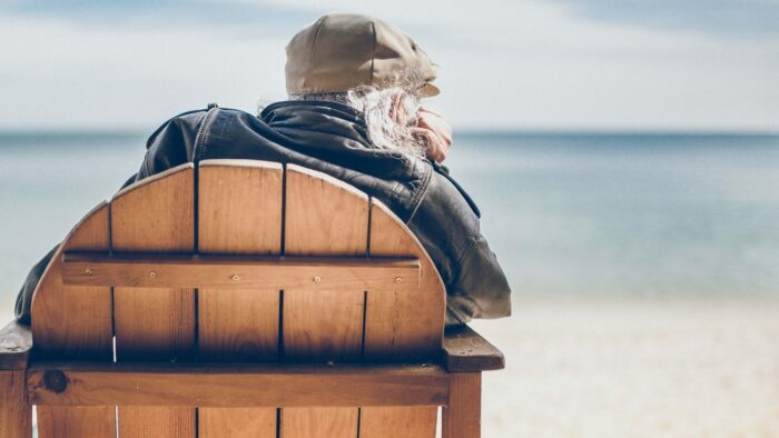 person sitting on brown wooden chair in seashore