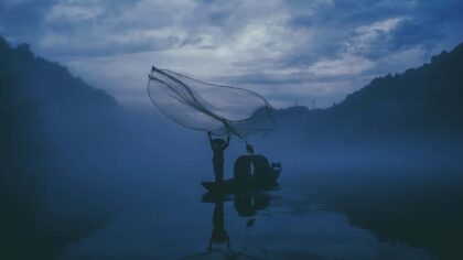 person fishing in a body of water during nightime