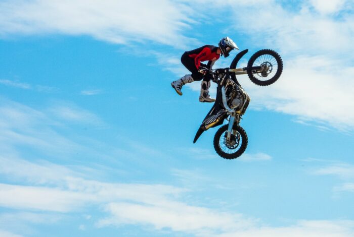 person wearing red and black jacket while holding motocross dirt bike