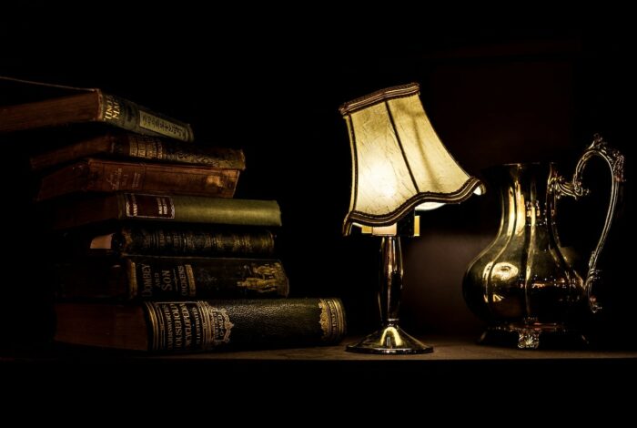 turned on desk lamp beside pile of books